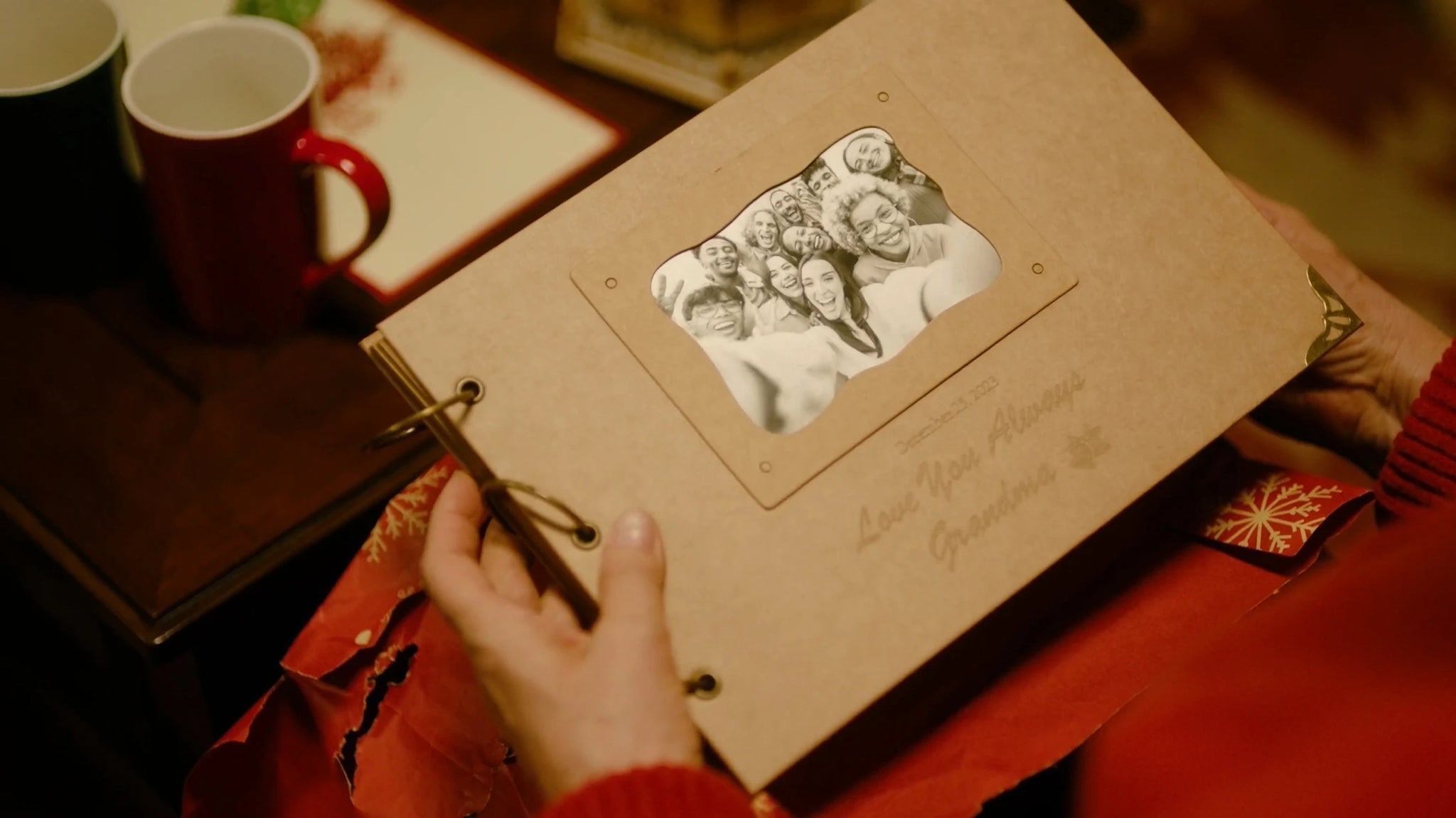 Someone holding a personalized photo album featuring engraved messages and a family photo on the cover.