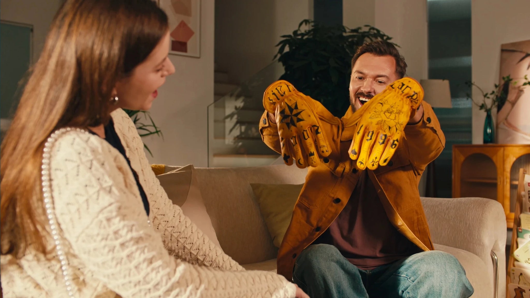 A man happily receiving a pair of personalized engraved orange gloves from a woman.