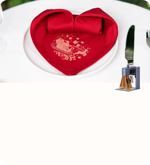 A red heart-shaped napkin engraved with a festive holiday design placed on a dining table.