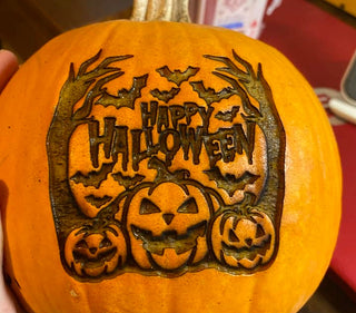A pumpkin engraved with the words “Happy Halloween” and spooky decorative elements.