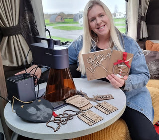 A small business owner sitting at a table with an LP4 laser engraving machine and the creative products she made.
