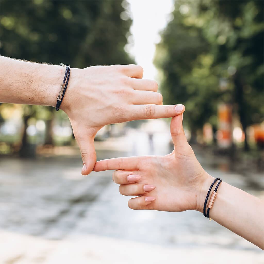 Man und Frau tragen die schwarzen geflochtenen Lederarmbänder.